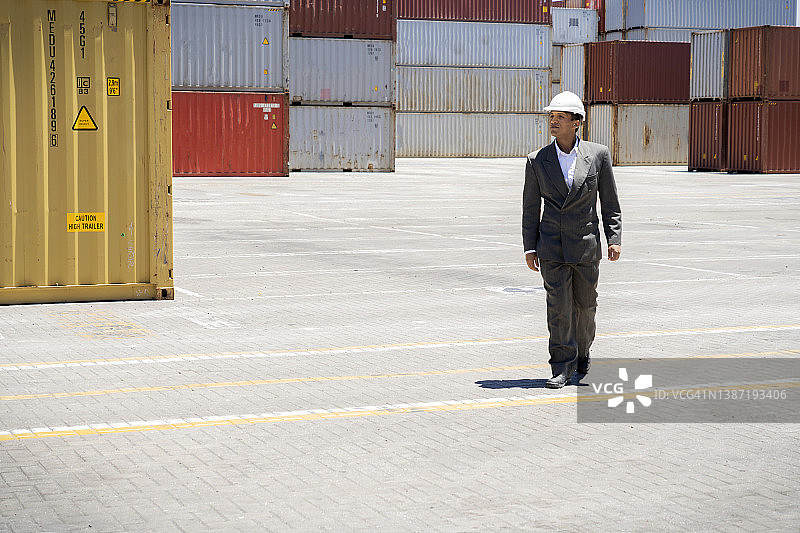 戴着安全帽的男报关员在货运场上行走图片素材