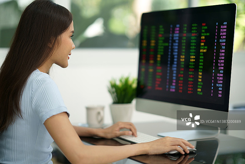 女人在办公桌上用电脑进行在线股票交易图片素材