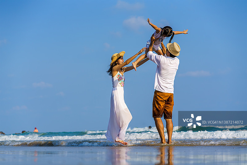 幸福的一家人在热带海滩日落时散步图片素材