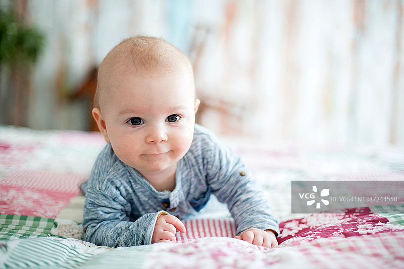 早上在床上玩耍的可爱微笑新生男婴图片素材