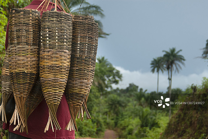 在利比里亚，一名男子肩上扛着在当地市场购买的手工鱼篓和其他用品。图片素材
