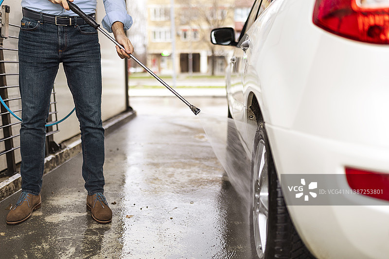 商人用水管清洗汽车轮胎图片素材