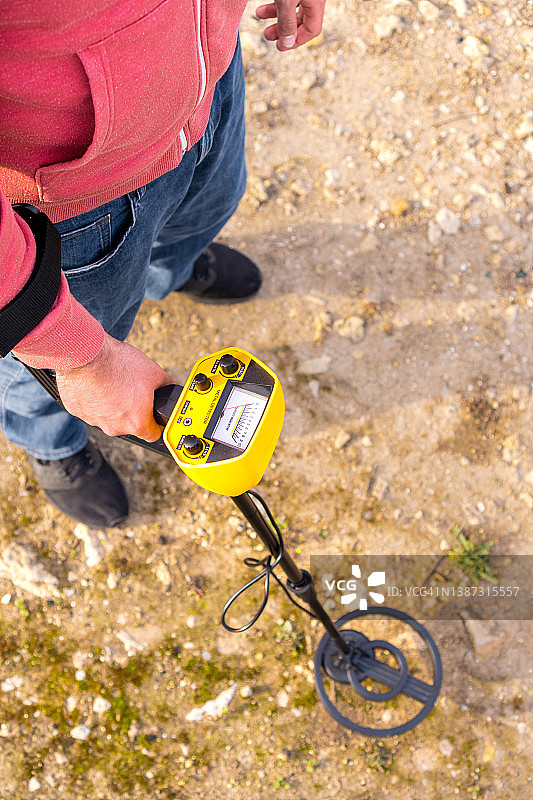 在阳光明媚的乡村早晨，使用金属探测器寻找物品的人的顶视图图片素材