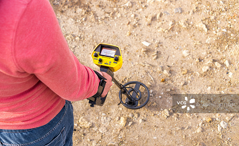 阳光明媚的郊外，人们使用金属探测器寻找物品的俯视图图片素材