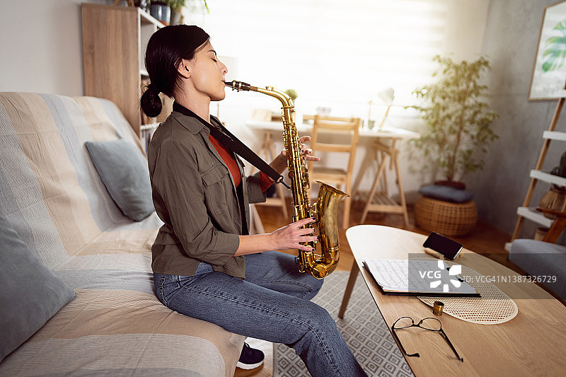 白人妇女与她的音乐老师进行视频通话，同时练习演奏萨克斯管图片素材