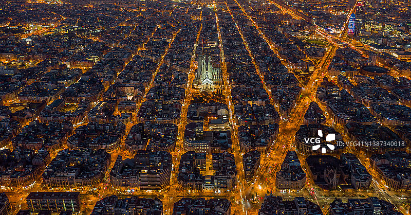 西班牙加泰罗尼亚巴塞罗那Eixample住宅区和著名大教堂的夜景航拍图片素材