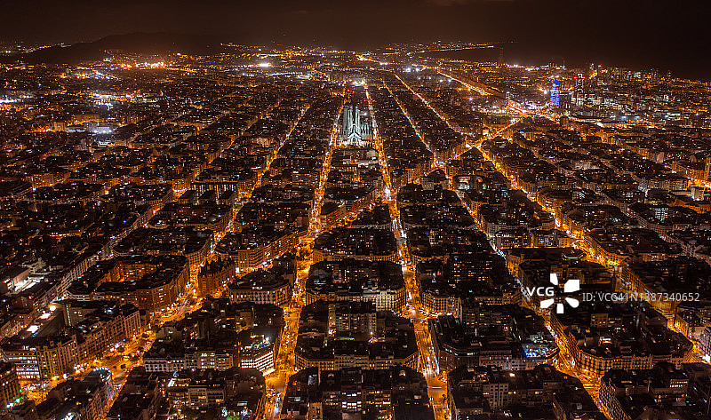 西班牙巴塞罗那Eixample住宅区、圣家堂和典型城市广场的夜景航拍图片素材