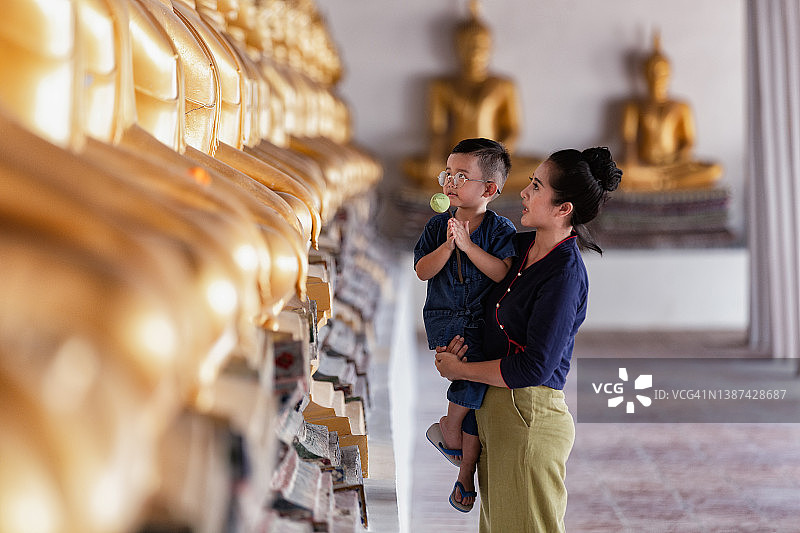 母子在泰国阿瑜陀耶普泰萨旺寺向佛像祈祷图片素材