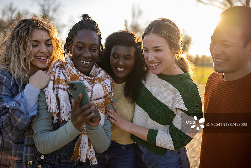 多种族朋友看着用手机拍摄的照片图片素材