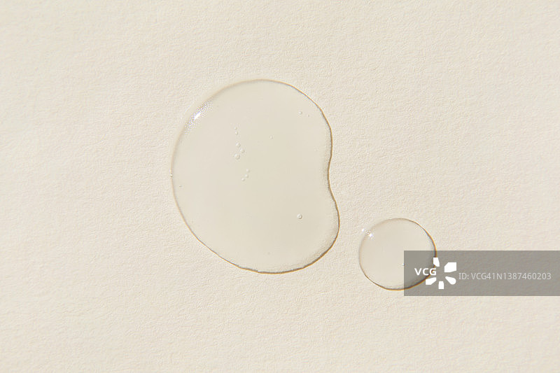 米色背景上的透明精华液滴图片素材