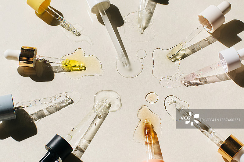 米色背景上滴有化妆品液体的移液器。美容产品含有多肽、神经酰胺、透明质酸凝胶、聚谷氨酸、精油、CBD、视黄醇、胶原蛋白。多任务的美。平躺，俯视图。图片素材