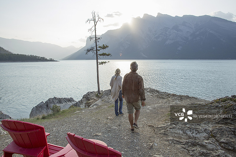 中年夫妇在湖岸边的红色扶手椅上放松图片素材