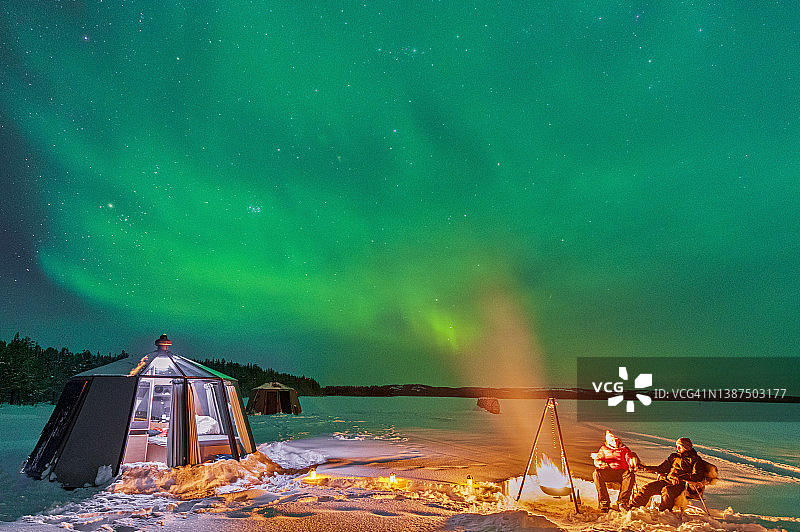 人们坐在拉普兰北极光下的篝火旁图片素材
