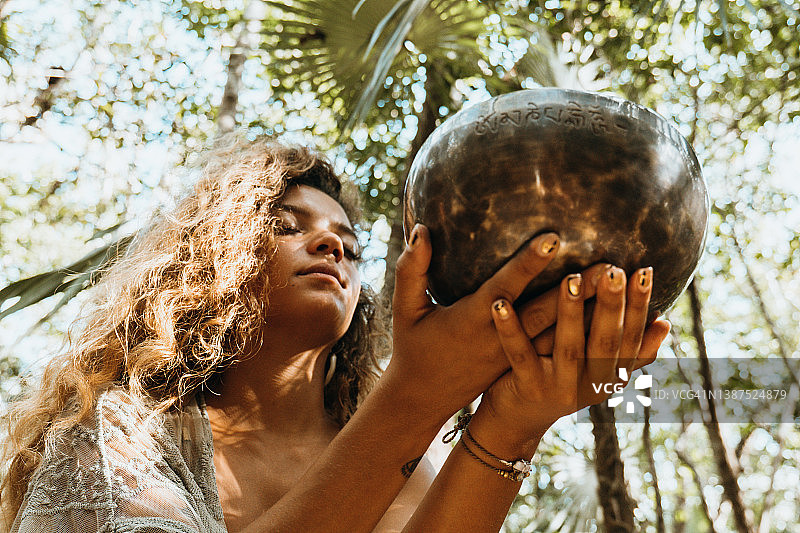 热带雨林中举着锣的混血女人图片素材