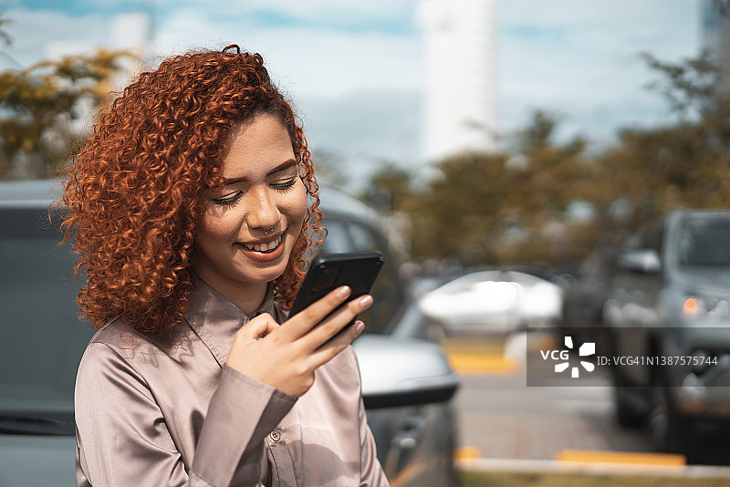 在停车场使用智能手机的女人图片素材