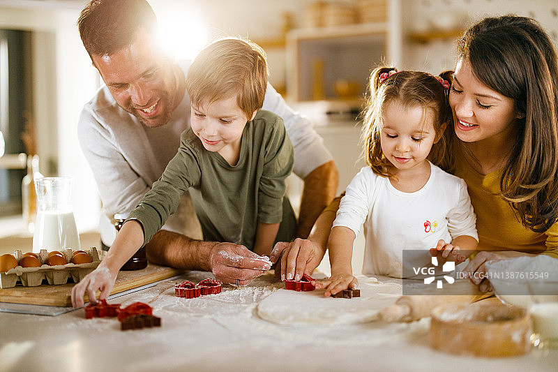 快乐的父母和孩子们在厨房合作制作饼干图片素材