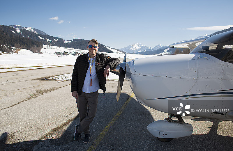 飞行员站在跑道上螺旋桨飞机旁图片素材