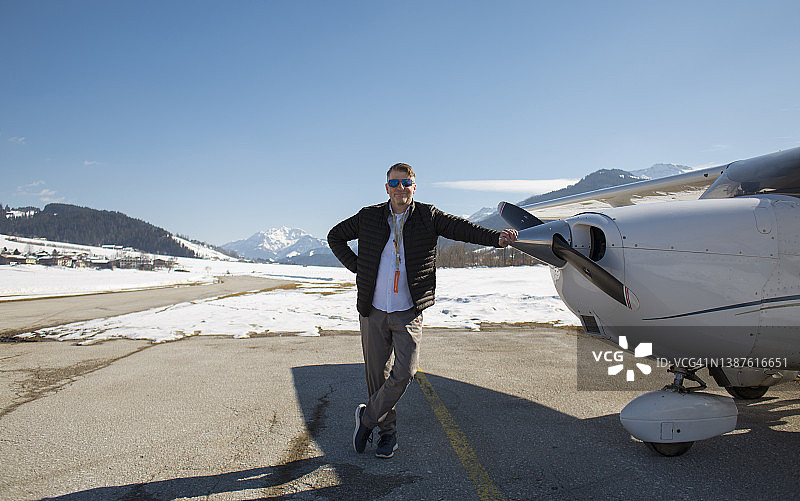 飞行员站在跑道上螺旋桨飞机旁图片素材