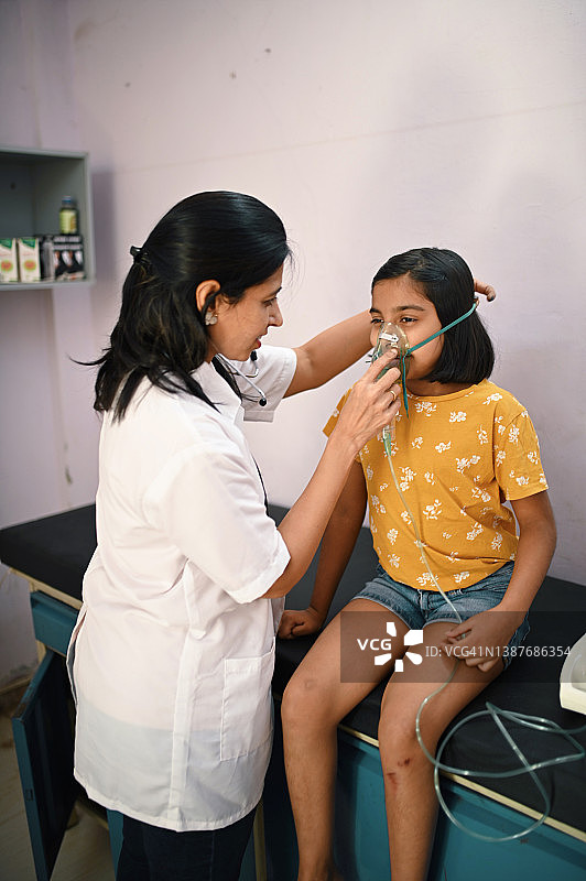 女医生帮助女孩佩戴雾化面罩图片素材