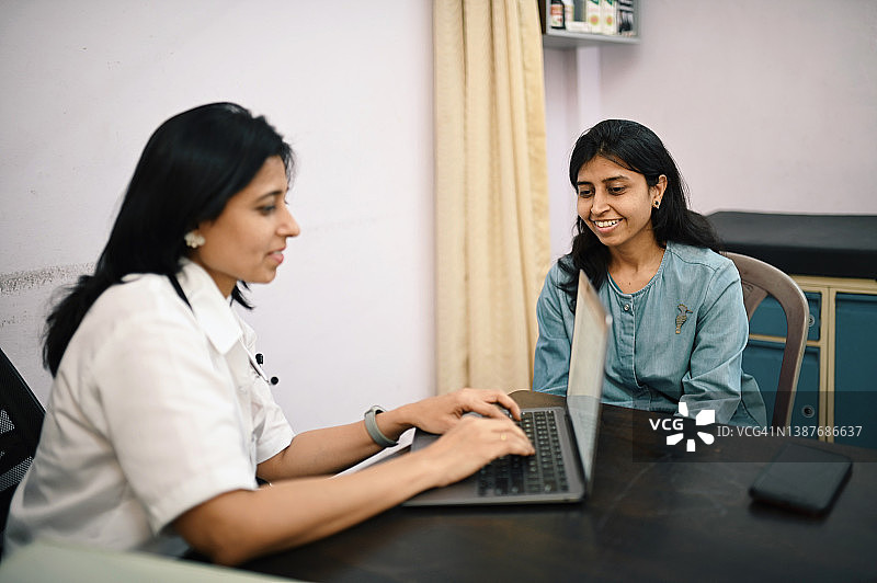 女医生和病人边用笔记本电脑边讨论图片素材