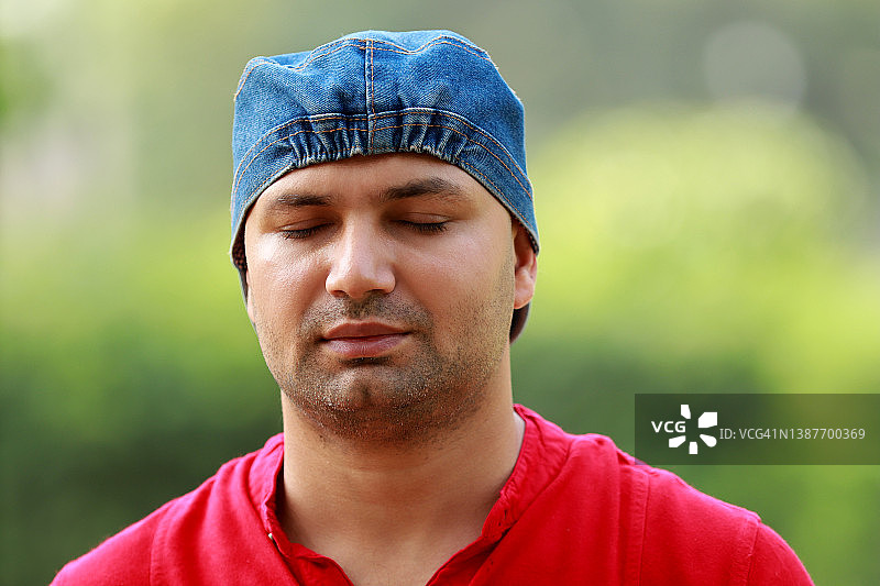 男人们闭着眼睛坐在公园里的肖像图片素材