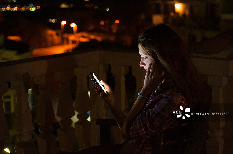 年轻女人在门廊外的智能手机上发短信图片素材