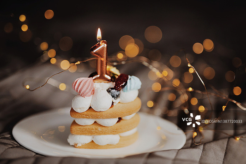 节日小水果蛋糕与花环背景上的蜡烛特写图片素材