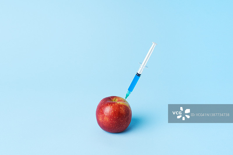注射器插入苹果，转基因食品概念图片素材