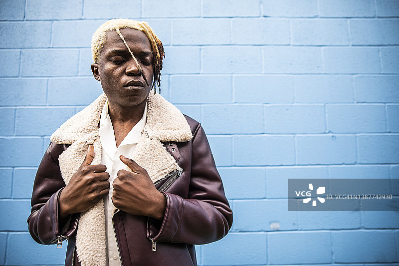 明蓝色墙前的时尚年轻人人像图片素材