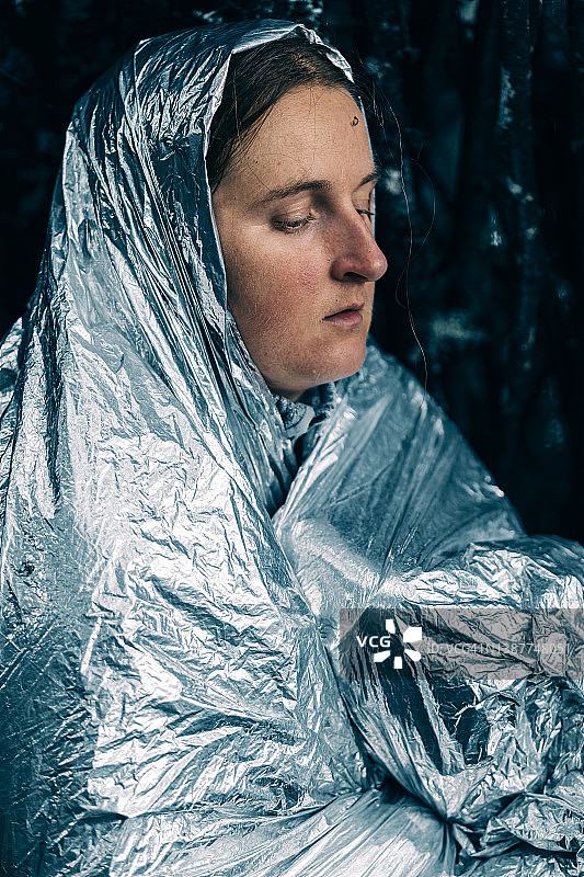 在野外银色救生毯中颤抖的女子肖像图片素材