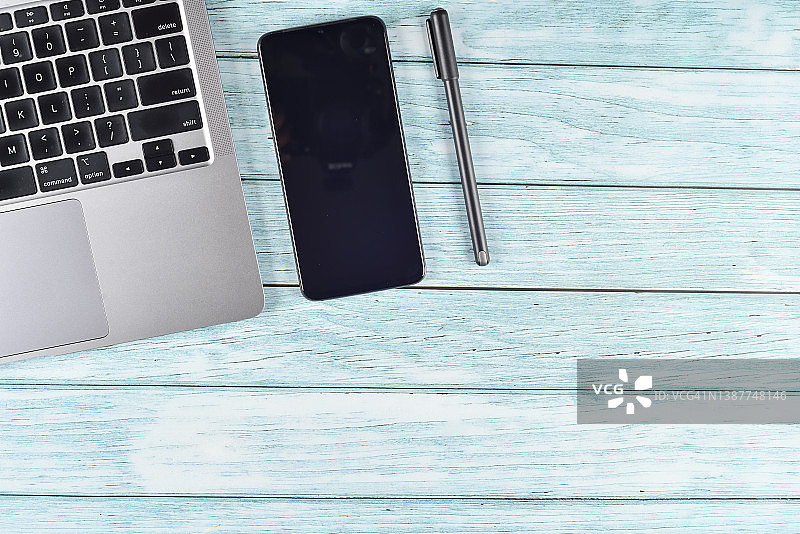 蓝色现代办公室桌子、智能手机和笔记本电脑键盘图片素材