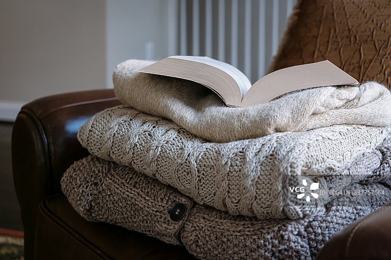 椅子上叠放的米色针织毛衣和书本图片素材