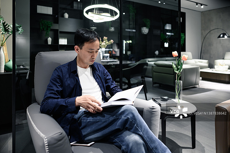 在客厅里阅读的年轻男人图片素材