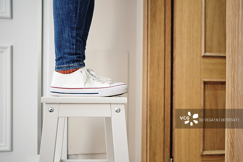 女人在房子里爬便携式梯子图片素材