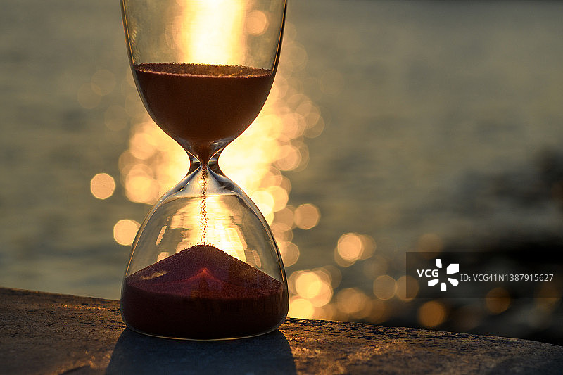 落日时分海面倒影映衬下的沙漏近景图片素材