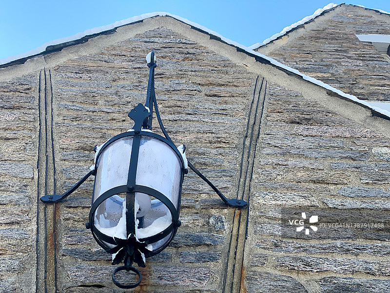 覆盖着新鲜积雪的都铎式住宅前门上的户外吊灯图片素材