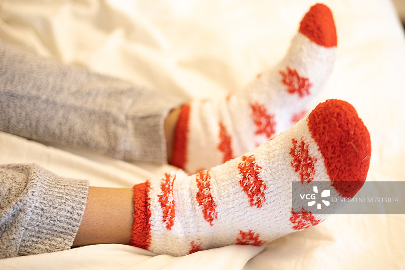 穿着暖和舒适袜子和运动裤坐在床上的少女图片素材