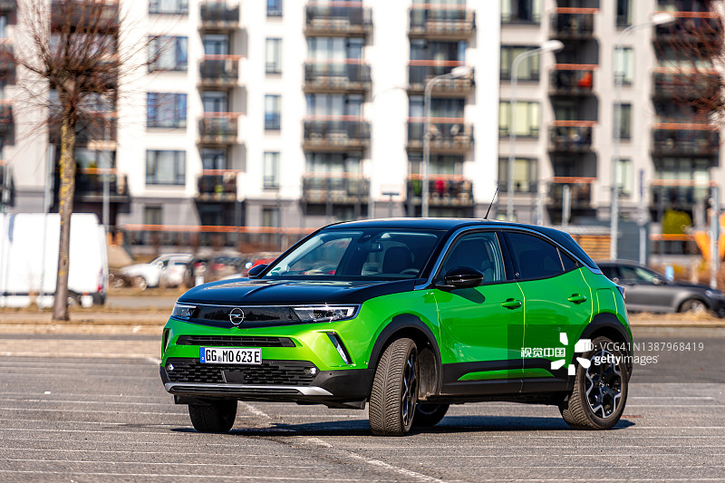 绿色电动汽车欧宝Mokka-e停在城市居民区停车位图片素材