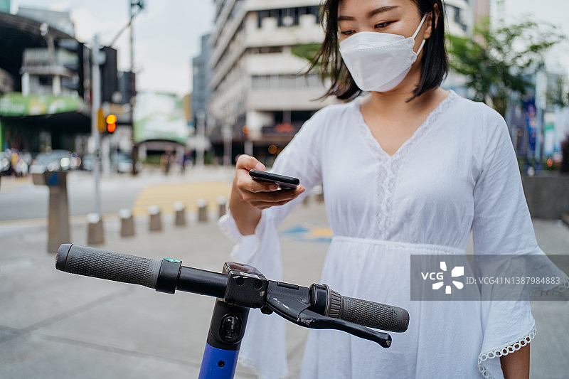 女游客扫描二维码，激活电动滑板车图片素材