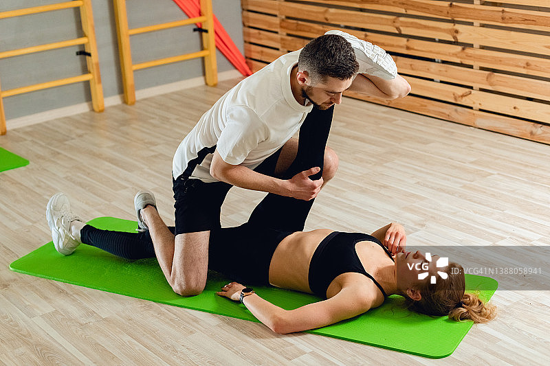 室内康复训练的两人：女子和男子进行健康锻炼，医生和健身教练指导图片素材