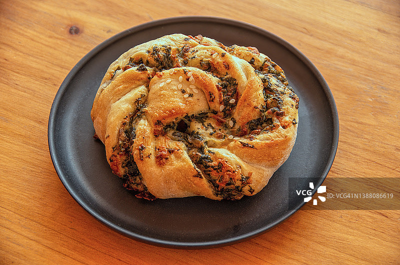 木桌上盘中的菠菜奶酪咸味面包卷图片素材