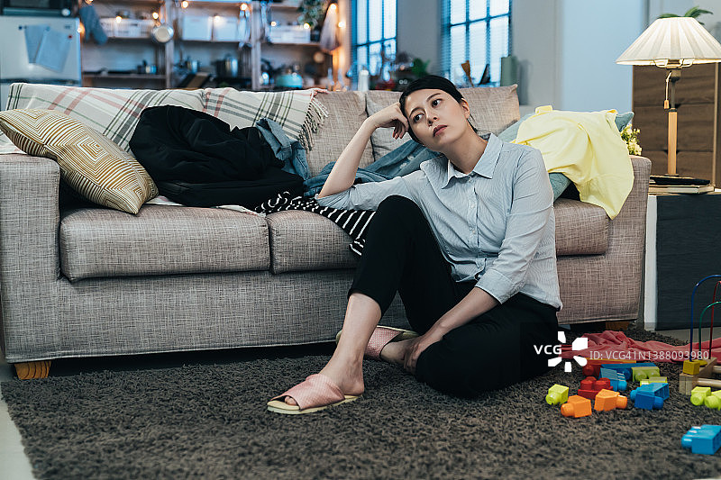 疲惫的亚洲妈妈坐在客厅沙发上图片素材