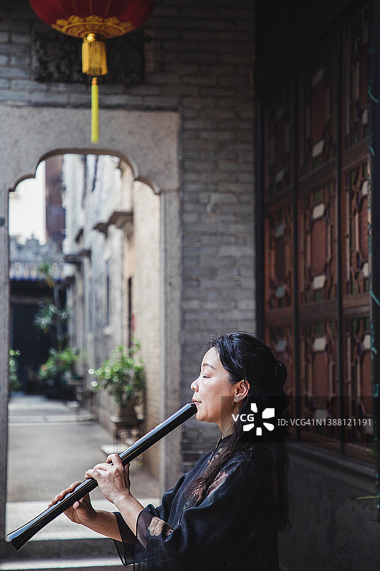 年长的亚洲女人在吹尺八图片素材
