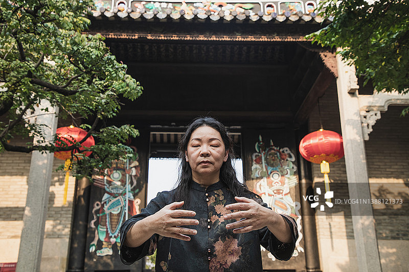 年长的亚洲女人在院子里练习太极图片素材