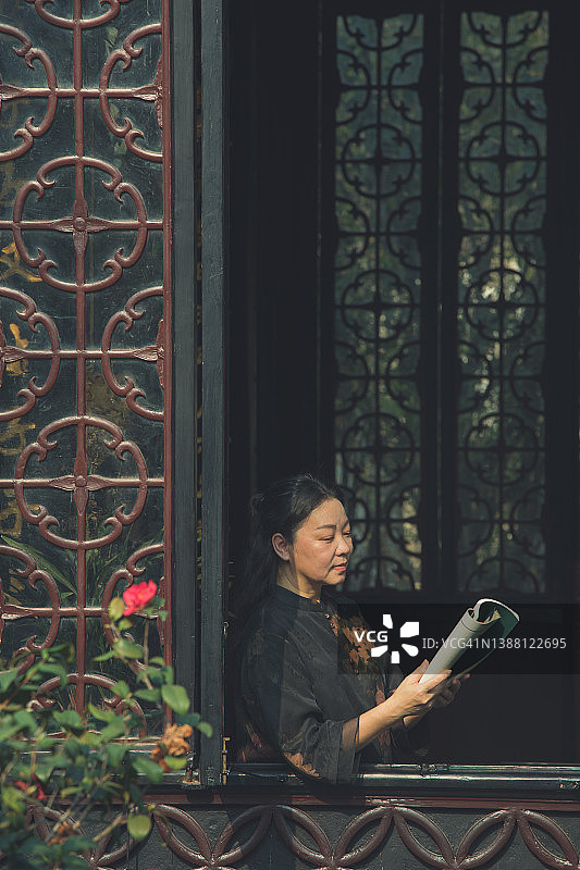 在窗边读书的亚洲老年妇女图片素材