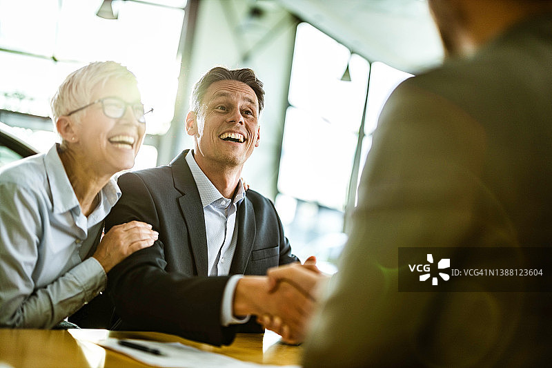 快乐的商务夫妇在办公室与他们的代理人达成协议图片素材