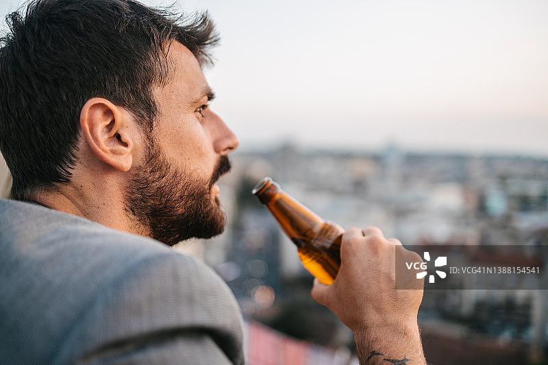 在屋顶喝啤酒的男人图片素材