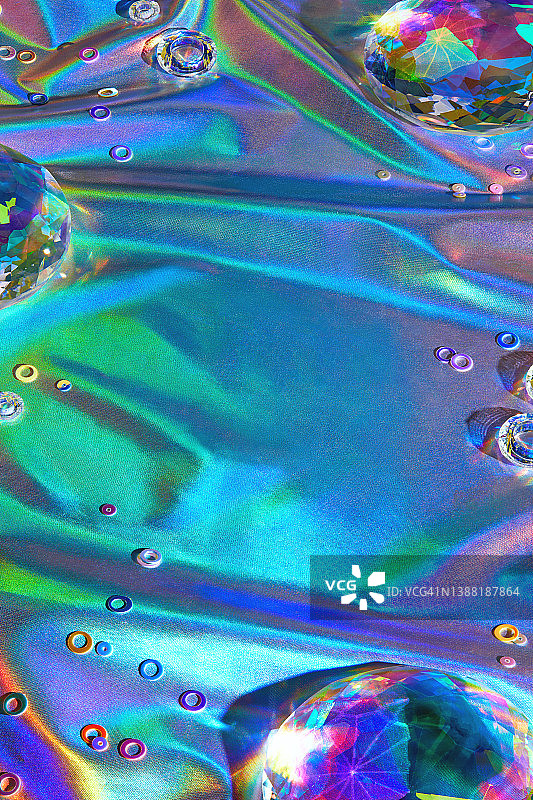 迪斯科霓虹反射彩虹全息纺织背景上的玻璃水晶和珠子图片素材