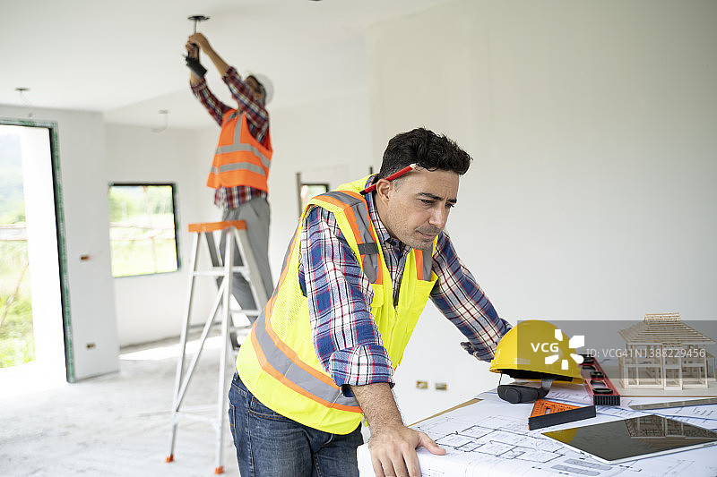 建筑工人在公寓里分析蓝图的全身照图片素材