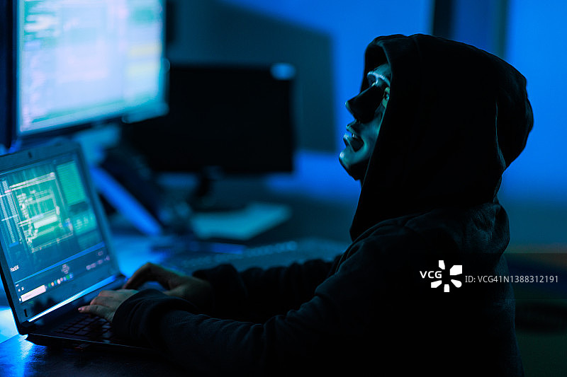 亚洲女黑客戴着黑色面具在服务器机房进行网络攻击图片素材